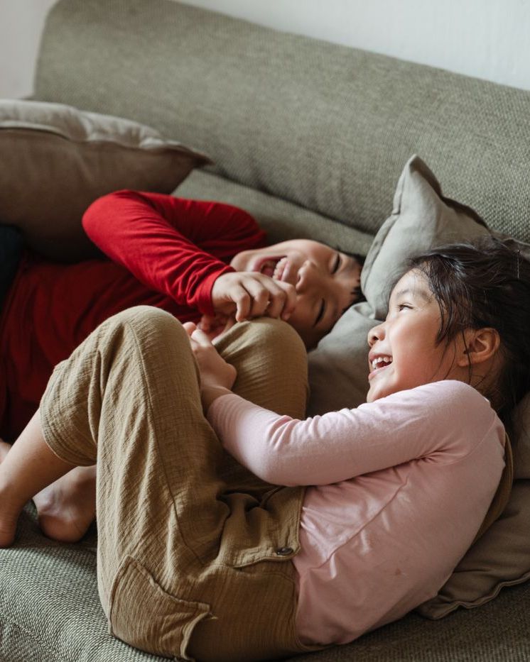 Two children laughing on a sofa